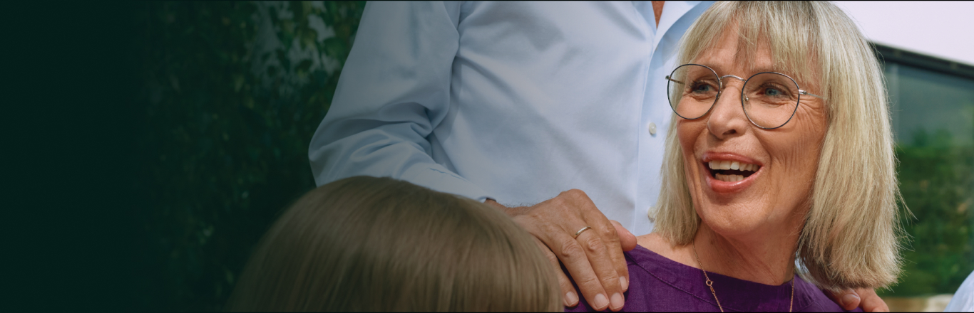 A person smiling sat down with other people outside