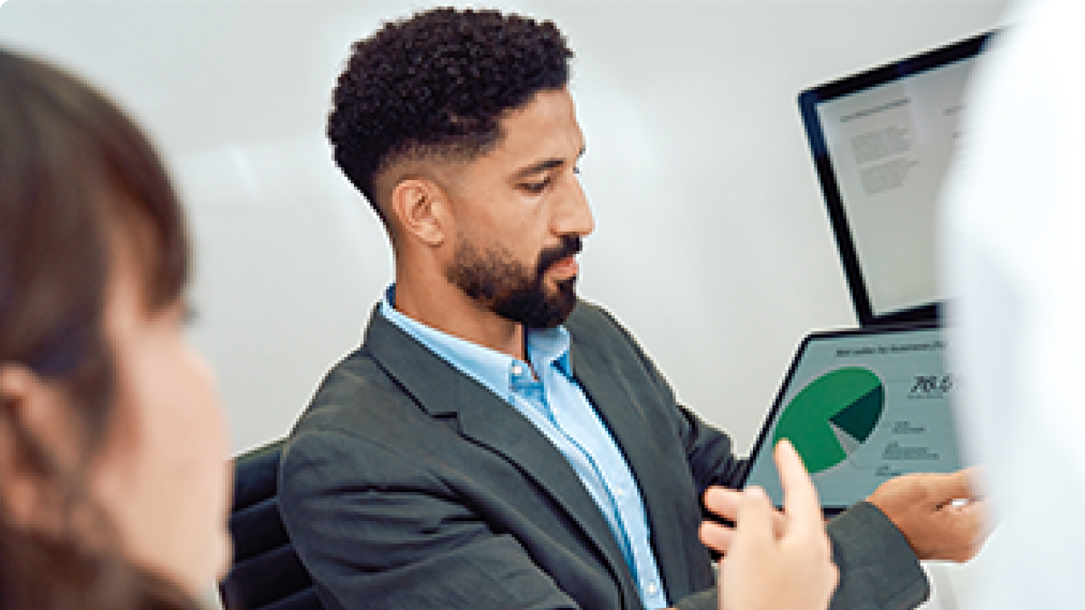 Two people looking at a tablet showing a pie chart